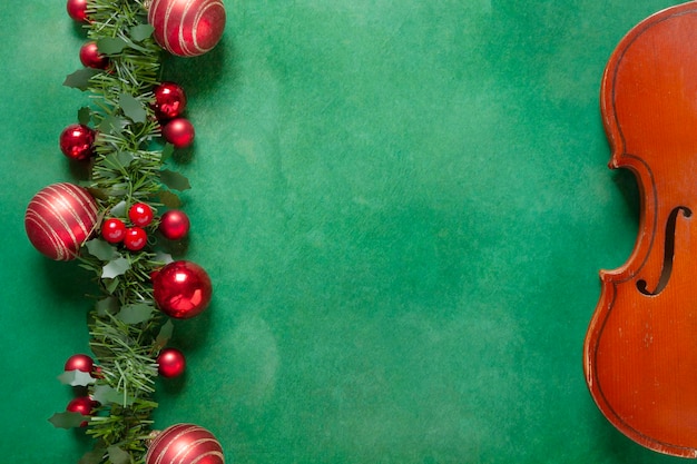 Viejo violín y hermosa decoración navideña roja sobre fondo verde Concepto de Navidad Año Nuevo Vista superior primer plano