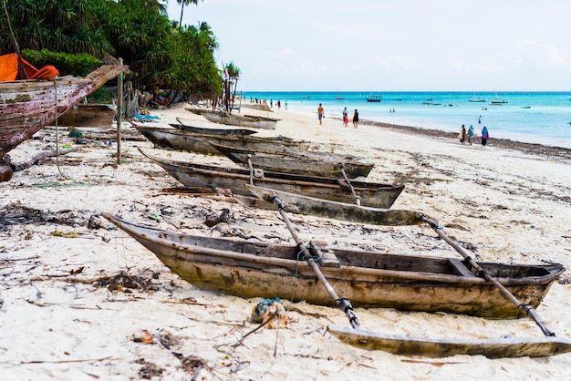 Viejos barcos de pesca de madera con remos en una playa de pueblo pesquero en zanzíbar