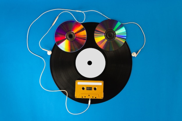 Viejos discos de vinilo y CD con cinta de audio crean un robot y auriculares con fondo azul