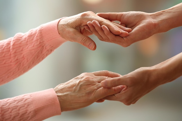 Viejos y jóvenes cogidos de la mano en primer plano de fondo claro