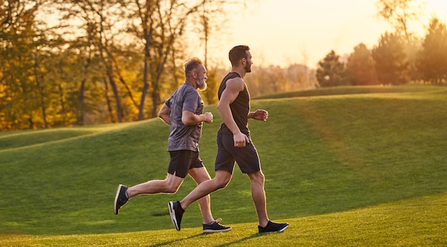 Los viejos y jóvenes deportistas corriendo en el parque verde.