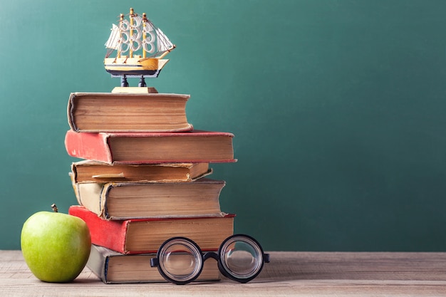 Los viejos libros escolares, libros de texto y útiles escolares se encuentran en una mesa de madera.