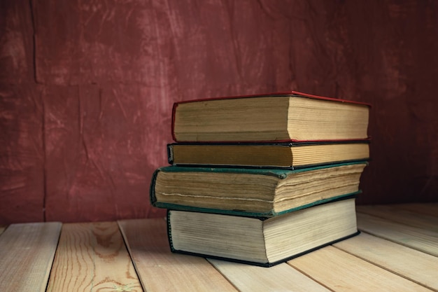 Viejos libros en una vieja mesa de madera hermoso fondo de pared roja