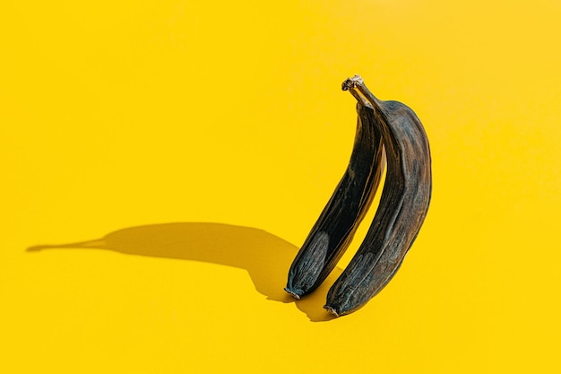 Viejos plátanos ennegrecidos arrugados sobre fondo amarillo