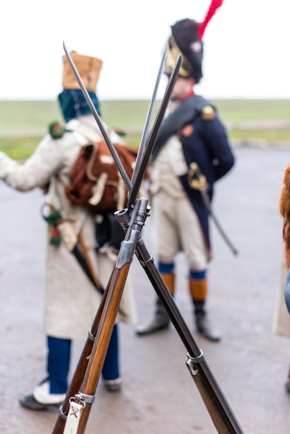 Los viejos rifles están apilados con una choza Soldados antiguos en el fondo