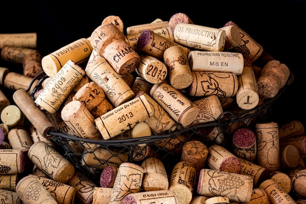 Viejos tapones de corcho de vinos franceses en una cesta de alambre.
