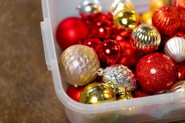 Viel rot-goldener Christbaumschmuck in einer Box. Vorbereitung auf das neue Jahr, Dekoration für den Neujahrsbaum. Foto in hoher Qualität