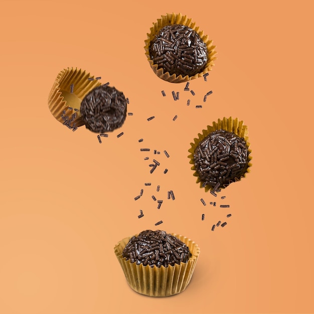 Viel veganer brasilianischer süßer Brigadeiro, der auf orangefarbenen Hintergrund fällt