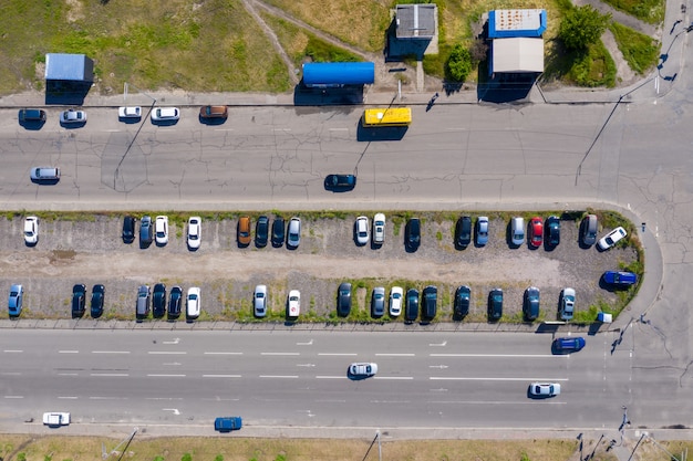 Viele Autos stehen auf einem spontan abfangenden Parkplatz zwischen zwei Alleen am Rande der Stadt.