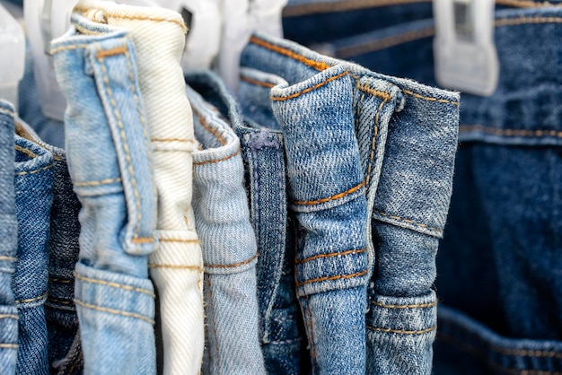 Viele blaue Jeans auf Kleiderbügeln zum Verkauf auf dem Straßenmarkt in Thailand aus nächster Nähe