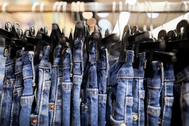 Viele blaue Jeans hängen an einem Regal im Bekleidungsgeschäft. Jeans oder Jeanshosen, die an einem Kleiderbügel hängen.