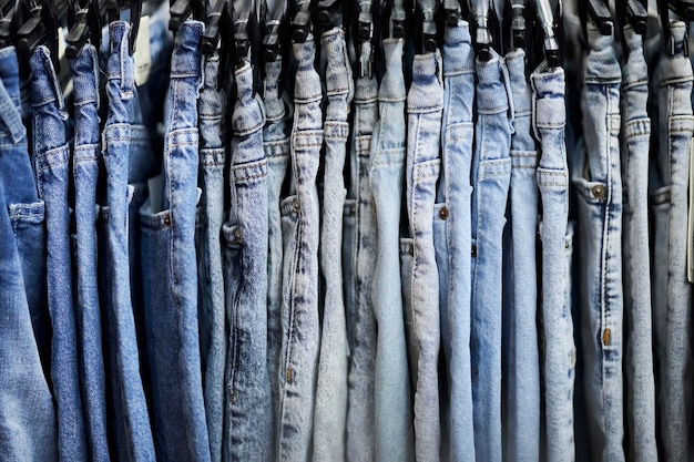 Viele blaue Jeans hängen an einem Regal im Bekleidungsgeschäft. Jeans oder Jeanshosen, die an einem Kleiderbügel hängen.