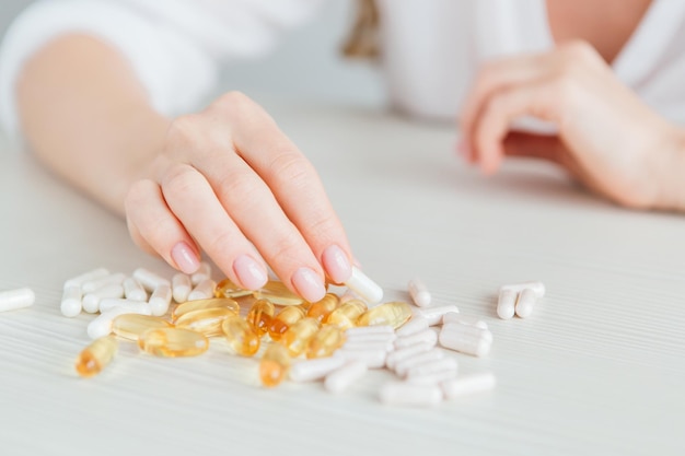 Viele bunte Kapseln mit Tabletten, Vitaminen, Nahrungsergänzungsmitteln in der Hand auf einer weißen Tischnahaufnahme. Tonen.