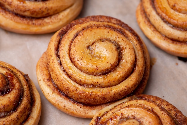 Viele frisch gebackene Brötchen mit Zimt auf Backpapier. Leckere Backwaren zu Hause kochen