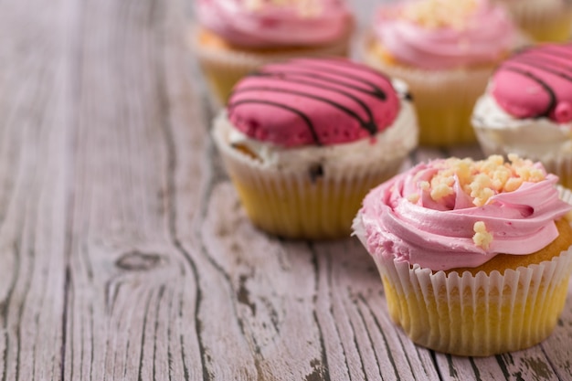 Viele frisch zubereitete Cupcakes auf einem Holztisch