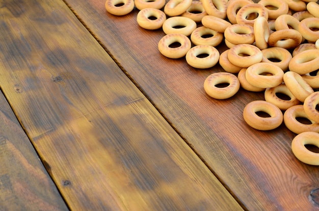 Viele frische gelbe Bagel liegen auf der Oberfläche des alten dunklen Holzes.