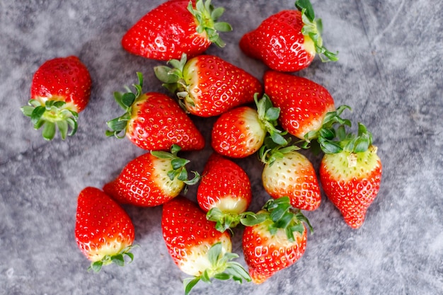 Viele frische rote Erdbeeren auf dunkler Oberfläche. Gesunde rote Beeren voller Vitamine