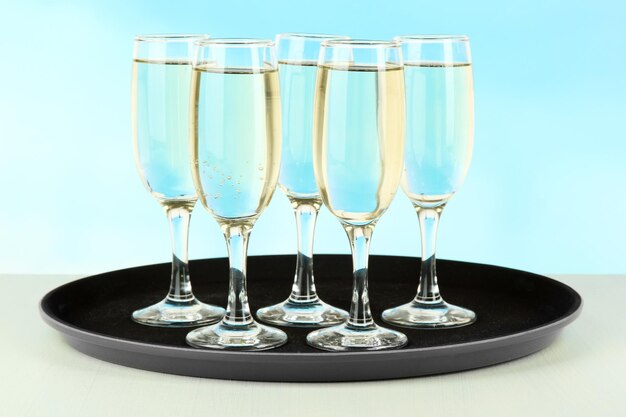 Viele Gläser Champagner auf dem Tablett auf dem Tisch auf blauem Hintergrund