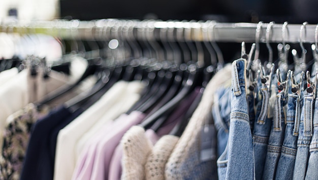 Viele hölzerne Kunststoffregale Kleiderbügel mit Denim-Kleidung männliche Mode-Dressing-Outfit