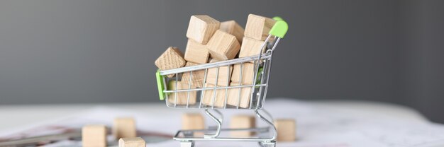 Viele Holzwürfel liegen im Spielzeug-Einkaufswagen-Nahaufnahme-Wohnungsbau-Konzept