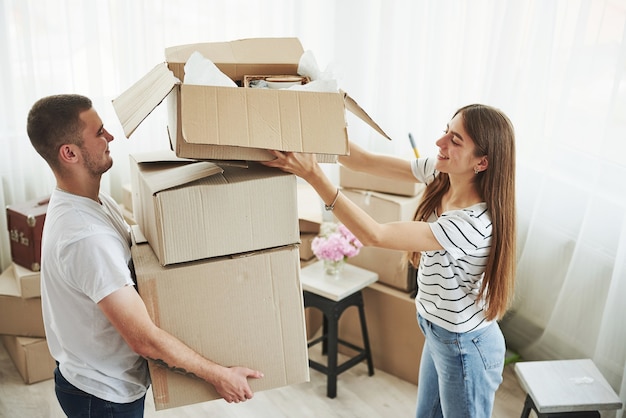 Viele Kisten. Fröhliches junges Paar in ihrer neuen Wohnung. Konzeption des Umzugs.