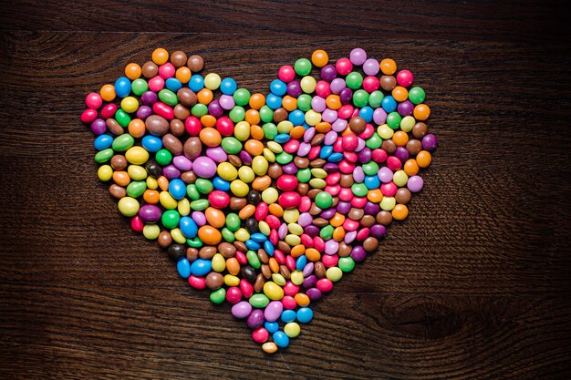 Foto viele kleine leckere schokoladenbonbons auf holzhintergrund