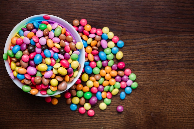 Viele kleine leckere Schokoladenbonbons auf Holzhintergrund