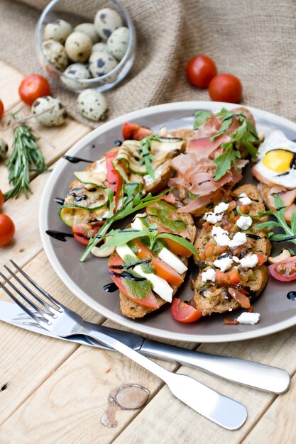 Viele leckere Bruschetta mit Käse, Tomaten, Wachtelei, Schinken, Lachs, geröstetem Gemüse und Kräutern