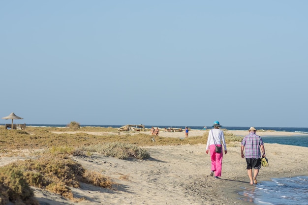 Viele Leute gehen im Frühlingsurlaub am Strand in der Nähe des Meeres im Sand spazieren