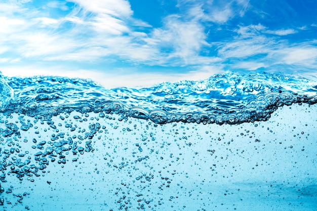 Viele Luftblasen im Wasser nah oben, abstrakte Wasserwelle mit Blasen auf einem Hintergrund des blauen Himmels