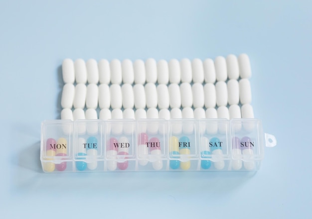 Viele Medikamentenpillen auf blauem Hintergrund. Verstreute weiße Pillen auf blauem Tisch