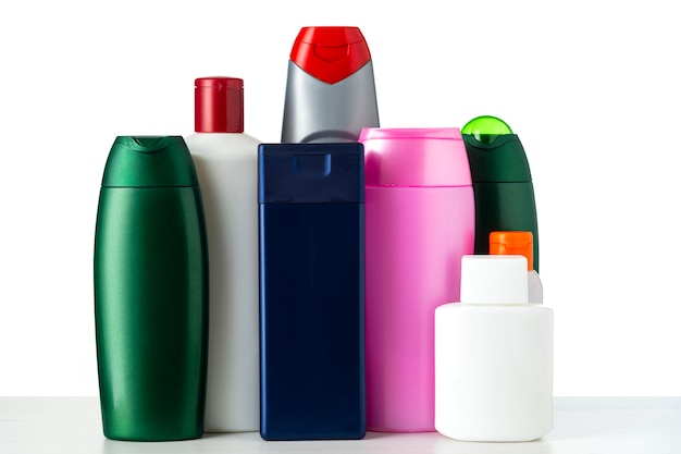 Viele namenlose Plastikflaschen in verschiedenen Farben unter einem Kosmetikprodukt auf weißem Hintergrund