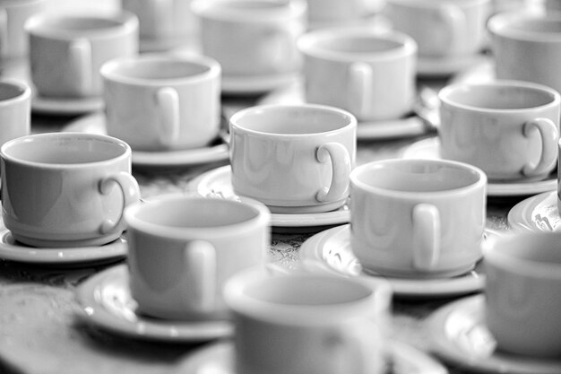 Viele Reihen von reinweißen Tassen mit Tellern für Kaffee- oder Teepausen