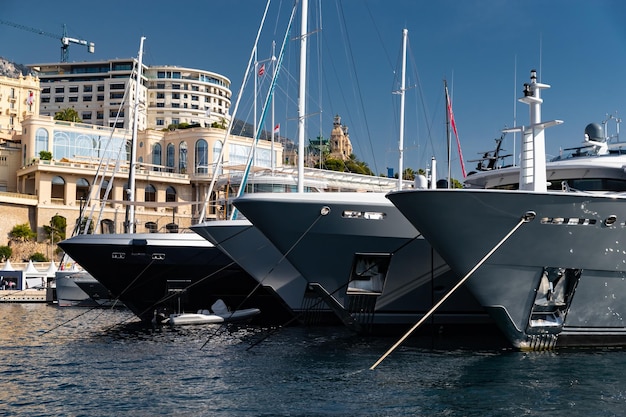 Viele riesige Yachten sind im Hafen von Monaco an einem sonnigen Tag Monte Carlo Mountain ist im Hintergrund glänzend ...