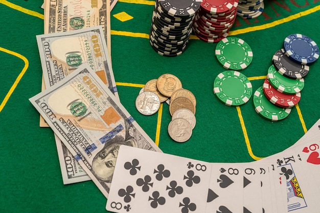 Viele Spielkarten verteilen sich mit farbigen Chips und Dollarscheinen auf dem Pokertisch Poker-Glücksspiel-Konzept