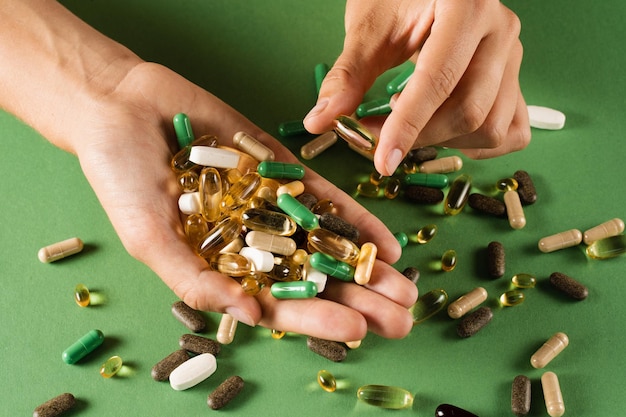 Viele verschiedene Pillen zur Behandlung und Wiederherstellung der Gesundheit auf grünem Hintergrund Satz von Omega- und Zinkpillen Antioxidantien aus alterndem Lecithin und Adaptogen