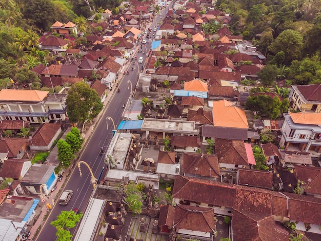 Viele Villen mit braunorangen Schindeldächern zwischen tropischen Bäumen auf dem Himmelshintergrund in Ubud auf Bali Sonne scheint auf sie Horizontales Luftbild