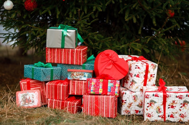 Viele Weihnachtsgeschenke unter dem lebenden Baum draußen Grüne, rote und weiße Farbe Weihnachten und Neujahr