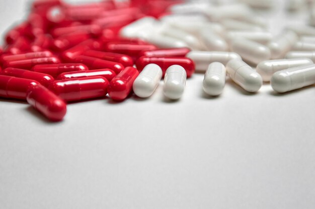 Viele weiße und rote Kapselpillen auf einem bunten Hintergrund. Nahrungsergänzungsmittel und Medikamente