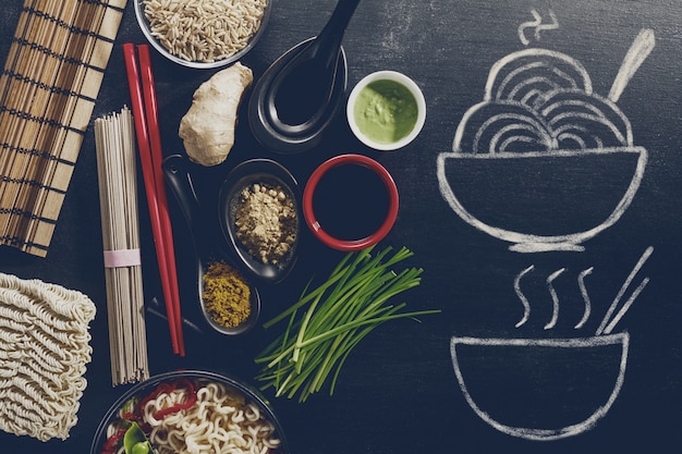Vielfalt Verschiedene Zutaten zum Kochen leckere orientalische asiatische Lebensmittel mit Hand gezeichneten Fertig Dish auf Tafel. Draufsicht mit Kopierraum. Dunkler Hintergrund. Über.