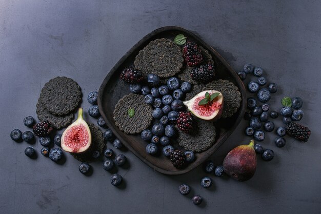 Vielzahl von Beeren und Feigen mit schwarzen Crackern