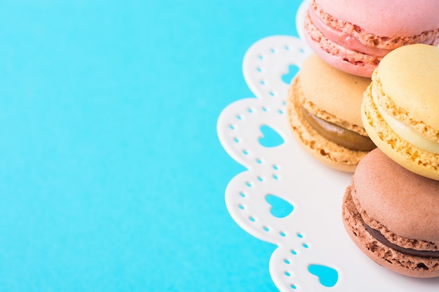 Vielzahl von den mehrfarbigen rosa grünen gelbbraunen Mokka-Kaffee Macarons, die auf Kuchen gestapelt werden, stehen auf Türkis-Hintergrund