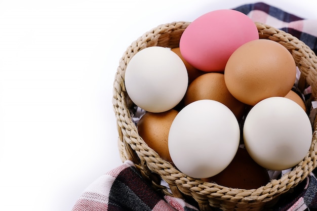 Vielzahl von Eiern im Weidenkorb, mit einem weißen Hintergrund.
