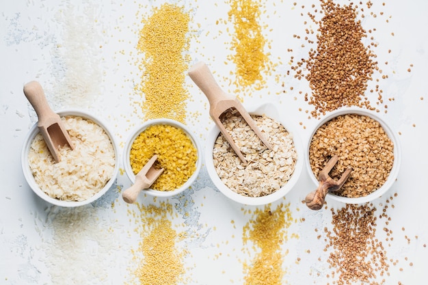 Vielzahl von Getreideflocken Reis, Hirse, Buchweizen, Haferflocken. Superfood in weißen Keramikschalen aus Holz