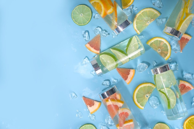 Vielzahl von kalten Getränken in Flaschen Sommergetränkte Wasserflaschen Limonade gesunde Cocktails mit verschiedenen Zitrusfrüchten Zitrone Orange Grapefruit Limette heller Hintergrund Kopierraum