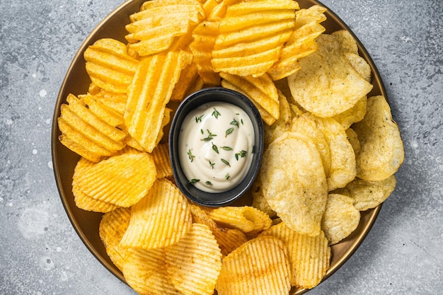 Vielzahl von Kartoffelchips in einem Teller serviert mit Dip-Sauce Grauer Hintergrund Ansicht von oben