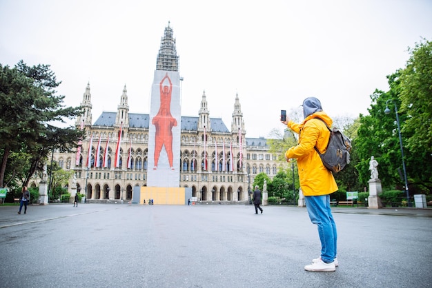 Viena Austria 16 de mayo de 2019 hombre viajero turista tomando fotos por teléfono en el ayuntamiento de Viena en el fondo