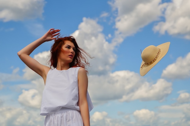 El viento sopla el sombrero de la cabeza de la mujer