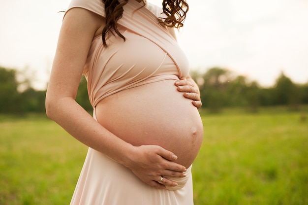 Vientre de una mujer embarazada al atardecer. Chica embarazada sintiendo el bebe