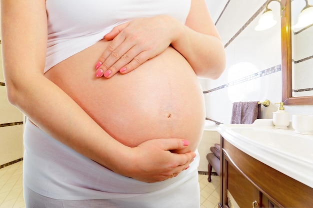 Vientre de una mujer embarazada en el baño.